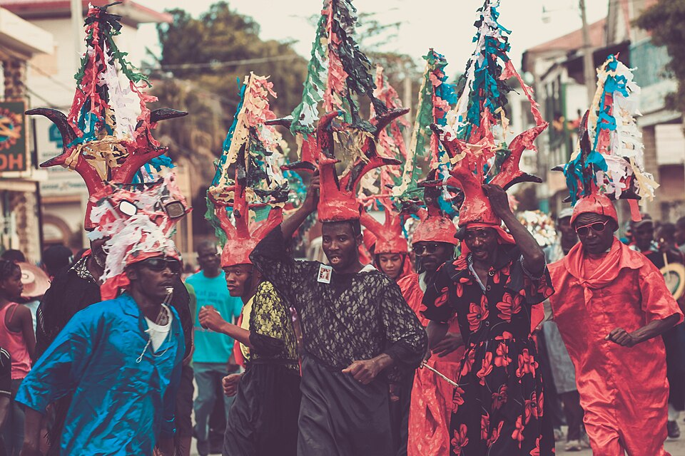 Costumed carnival performers in Jacmel, Haiti, in bright blue and red